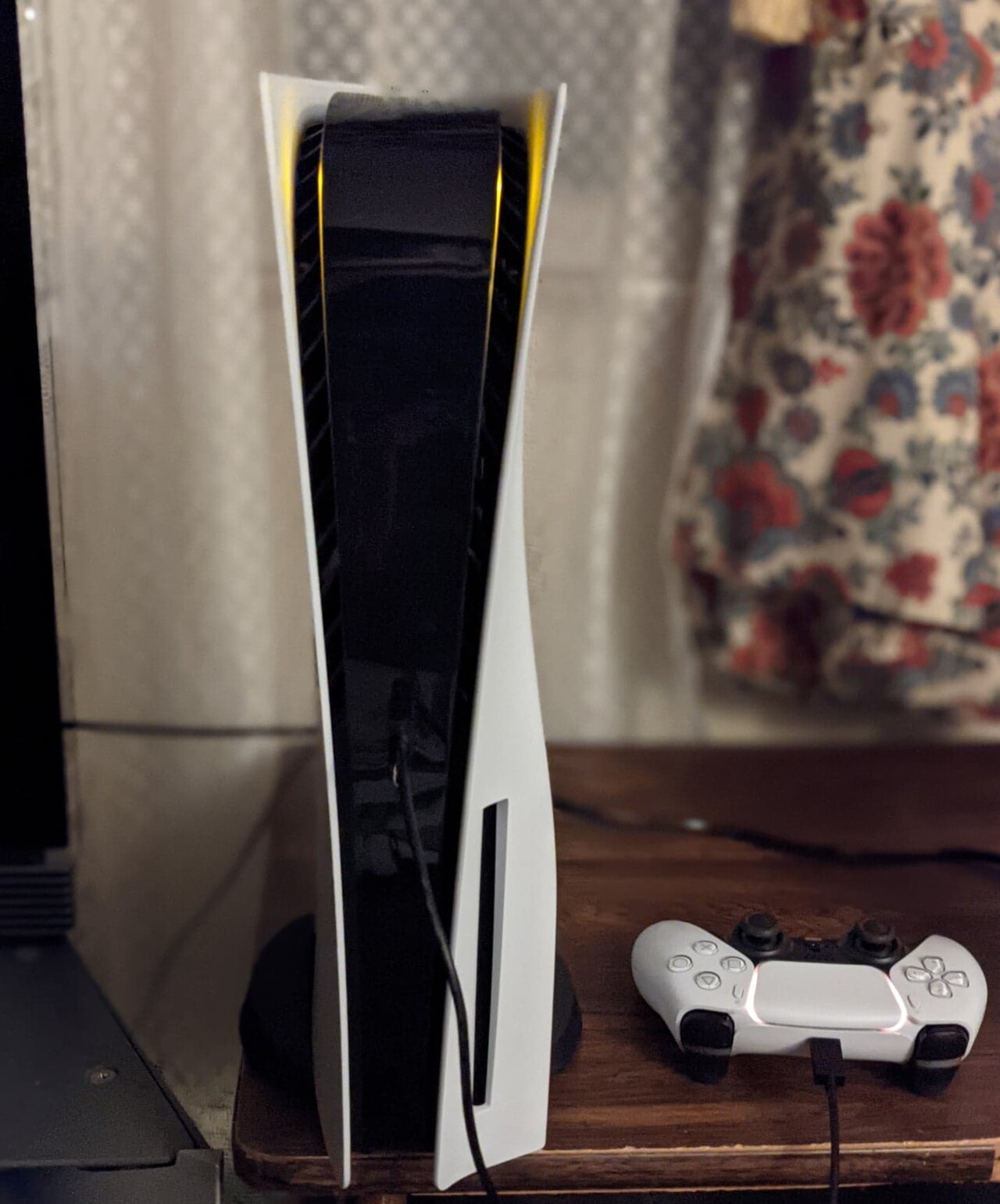 Console PlayStation 5 avec sa manette DualSense blanche, posée sur un meuble
