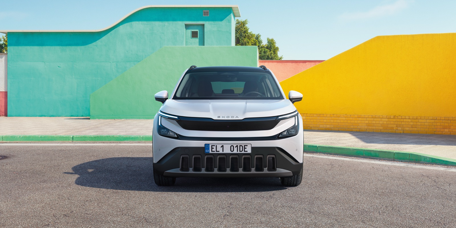 Skoda Epiq blanc vu de face devant des murs colorés
