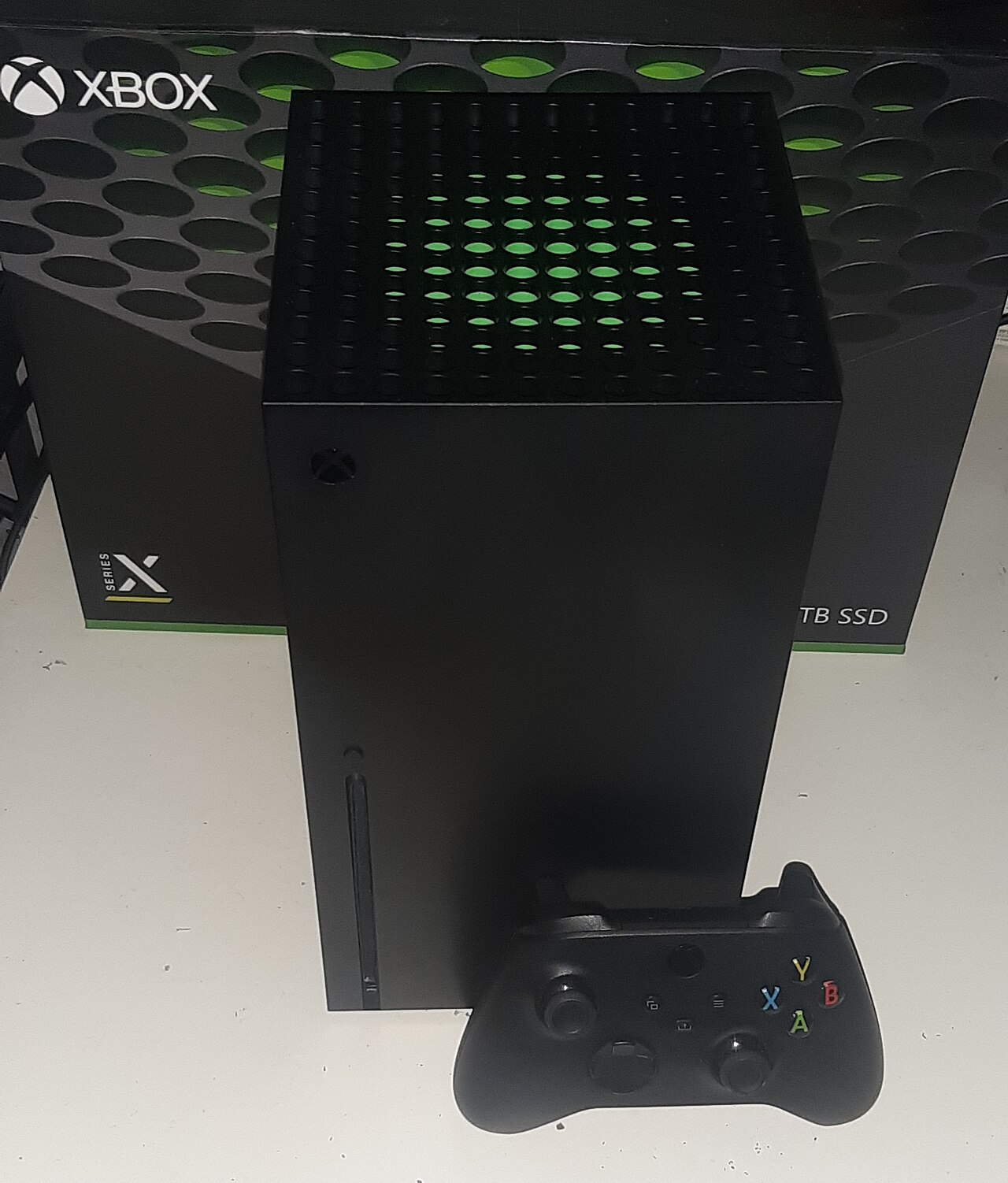 La console Xbox Series X noire posee devant sa boite, avec une manette Xbox