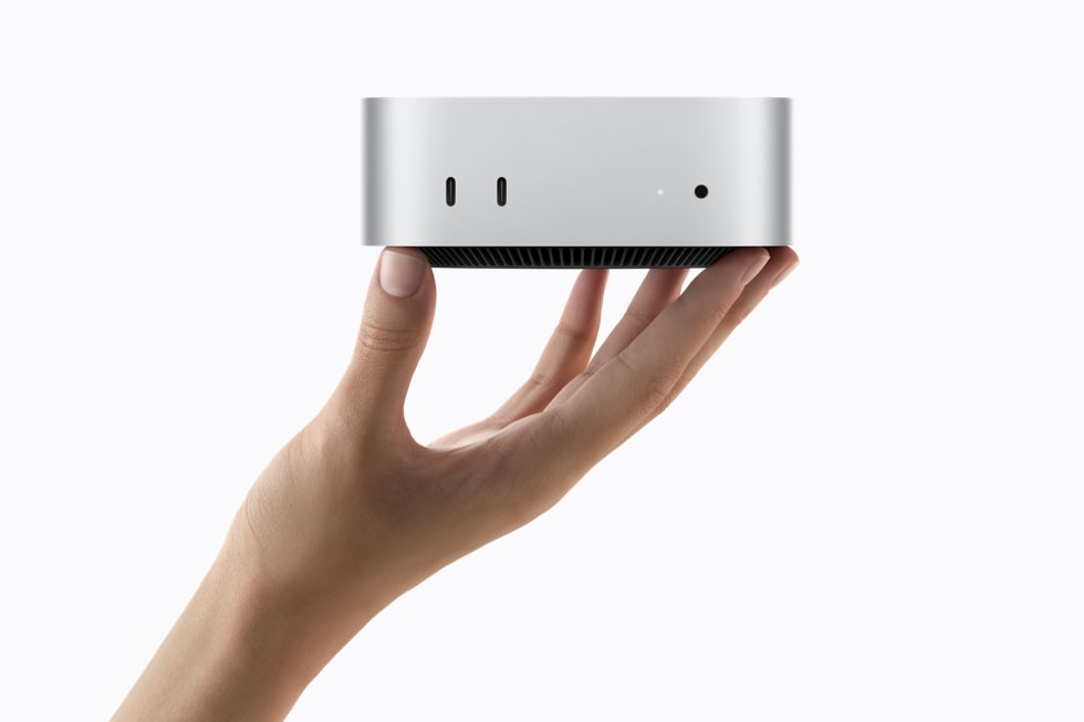 Le nouveau Mac mini d'Apple tenu dans une main, avec deux ports USB-C en façade