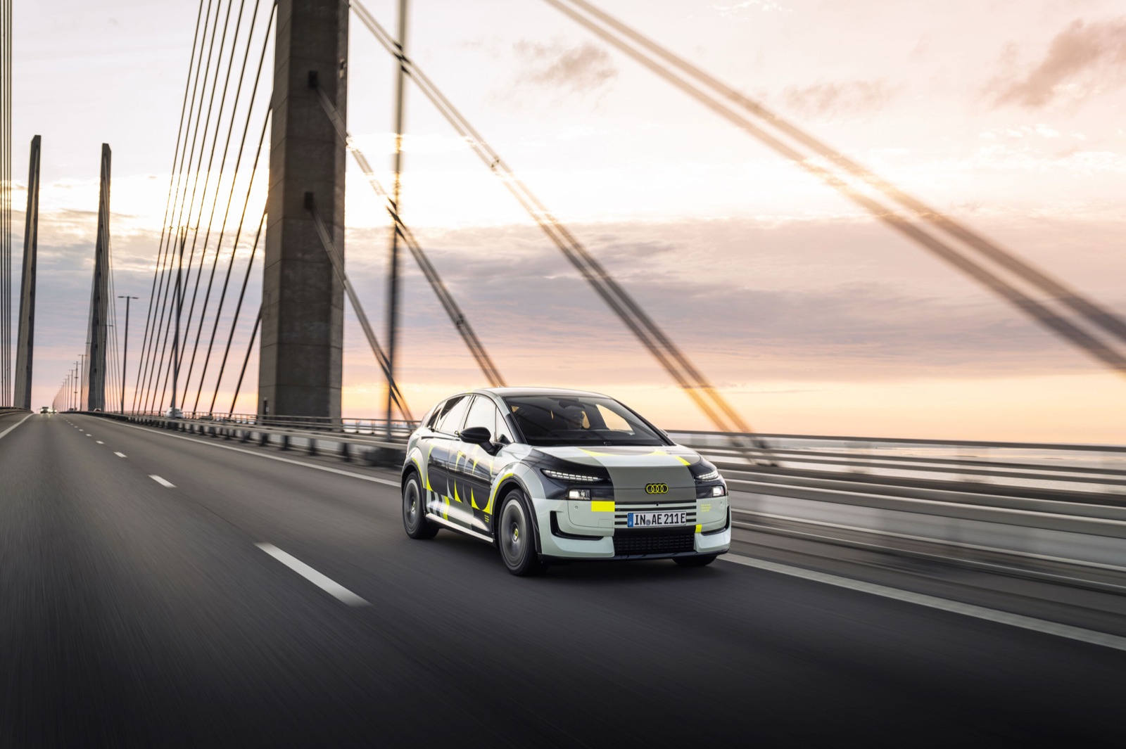 Prototype de l'Audi A2 e-tron, compacte electrique, roulant sur un pont au coucher du soleil