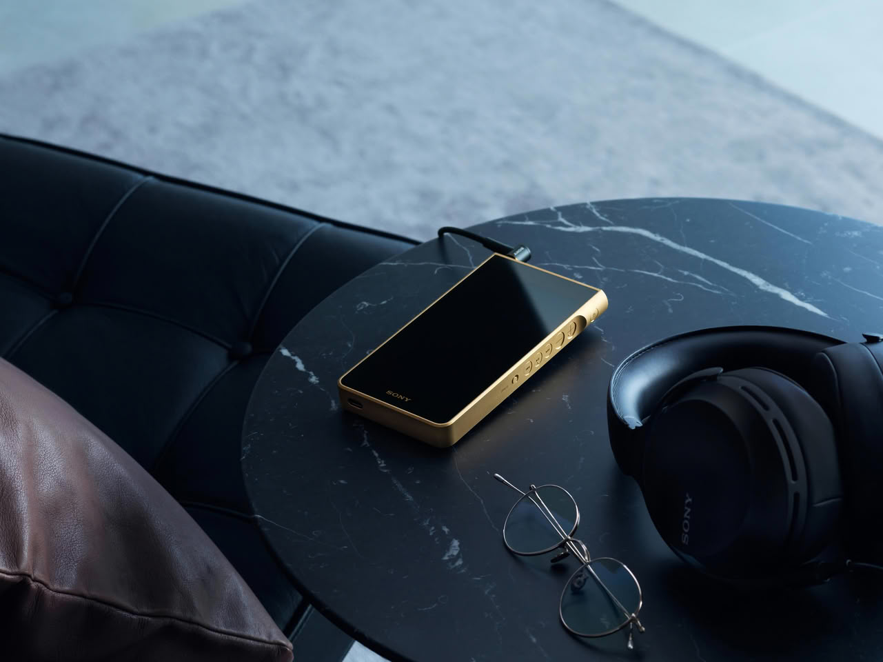 Baladeur audio Sony Walkman NW-WM1ZM3 plaqué or posé sur une table en marbre, à côté d'un casque Sony
