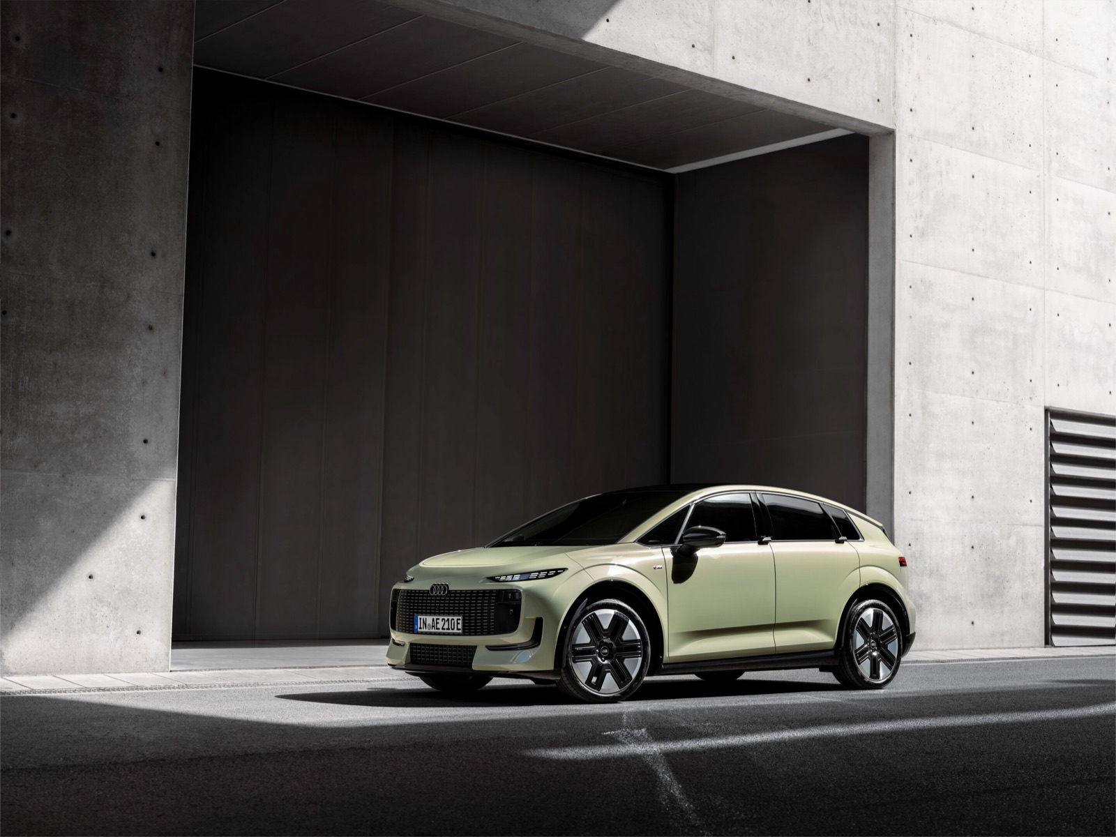 L'Audi A2 e-tron, compacte électrique de couleur claire, vue de trois quarts avant devant un mur de béton