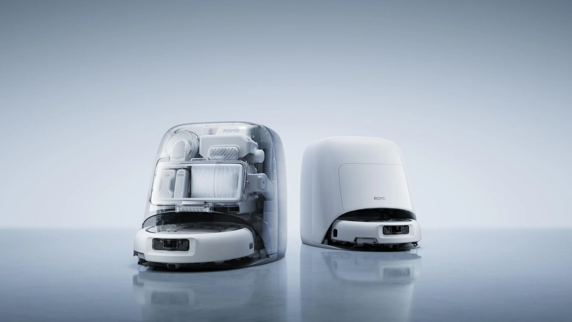 Les deux aspirateurs robots DJI ROMO 2 poses sur leur station, l'un au design transparent laissant voir les composants internes