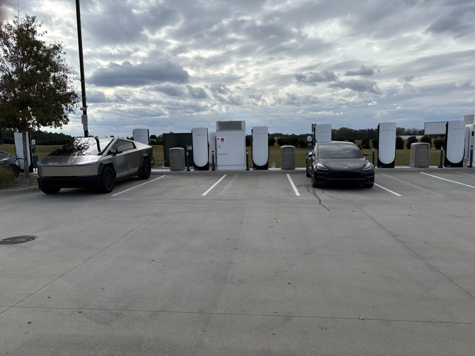Station de recharge Tesla Superchargeur avec plusieurs bornes blanches et véhicules électriques branchés