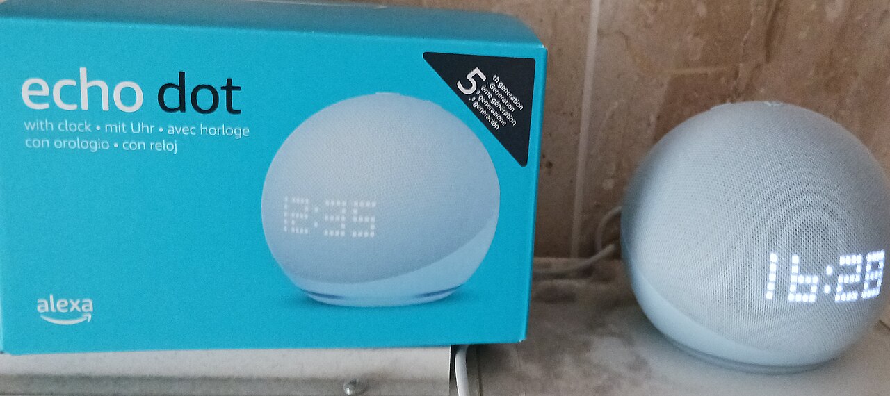 Enceinte connectée Amazon Echo Dot 5e génération avec horloge, posée à côté de sa boîte