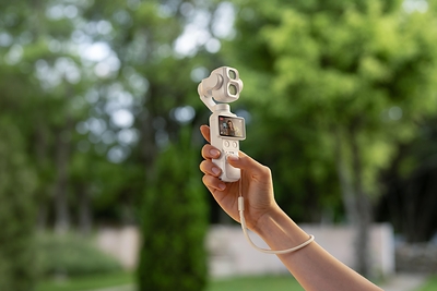 La caméra de poche DJI Osmo Pocket 4P en coloris Blanc perle, tenue à la main, nacelle et double objectif visibles
