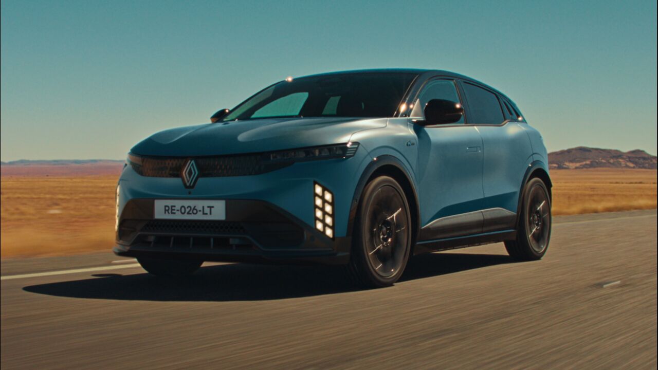 La Renault Mégane E-Tech restylée 2026 de trois quarts avant, sur une route, avec ses feux diurnes verticaux en losanges