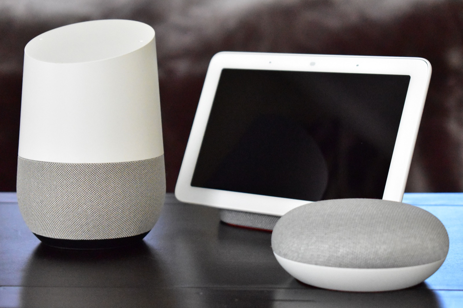 Une enceinte Google Home, un Nest Hub et un Google Nest Mini posés sur une table