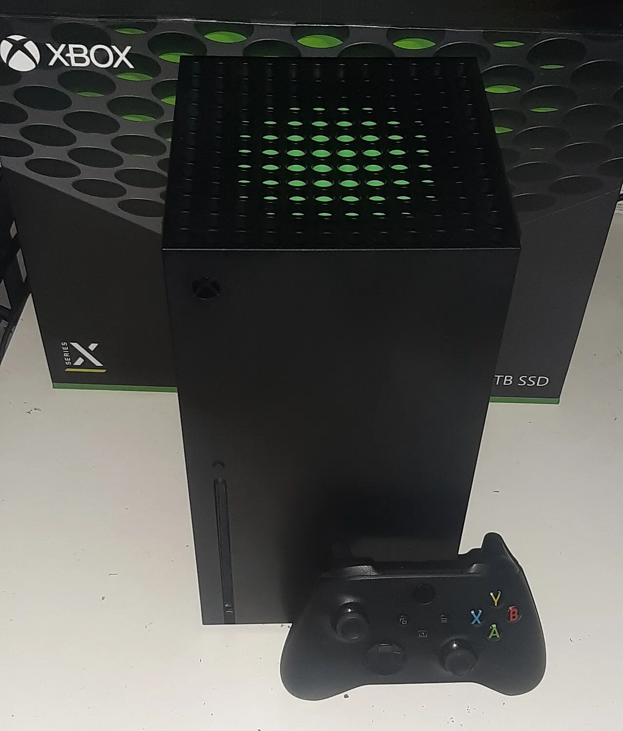 La console Xbox Series X noire posee devant sa boite, avec une manette Xbox