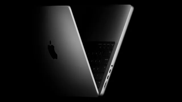 MacBook Pro Apple vu de profil, coque sombre et clavier, sur fond noir