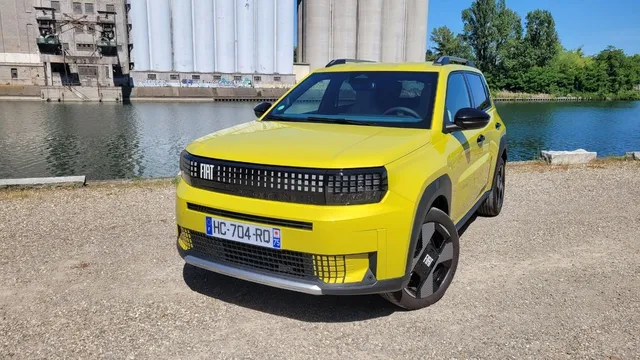 Fiat Grande Panda électrique jaune de trois quarts avant, immatriculée en France, devant un plan d'eau